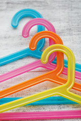 Colored hangers on a white wooden background. Fashion clothes hanging.