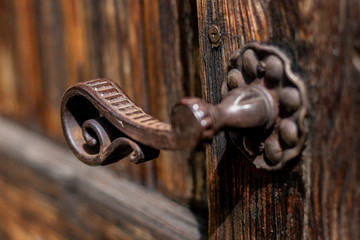 Old metal - iron, handle on a wooden door.