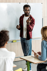 african american student in glasses standing near blackboard