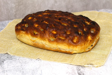 Italian bread with cheese, tomatoes and herbs. Focaccia on the table.