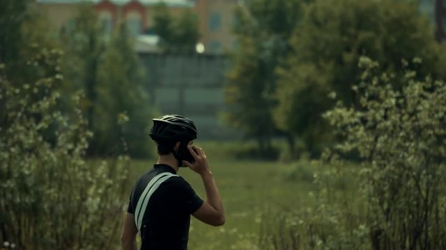 Cyclist Talking On Phone.Athlete Talking On Mobile Phone.Cyclist Using Mobile Phone.Man With Bicycle Talks On The Phone.Young Man Athlete Talking On Phone Near Field.Athlete Answer The Phone Call.