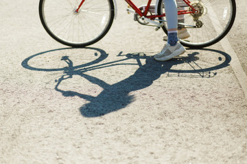 beautiful blonde girl in a denim jacket riding a red vintage bicycle in the parking lot near the new buildings