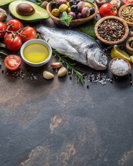 Raw dorado fish with spices and vegetables on the graphite board.