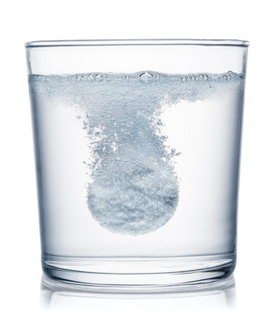Effervescent tablet dissolving in a glass of water. Clipping path.