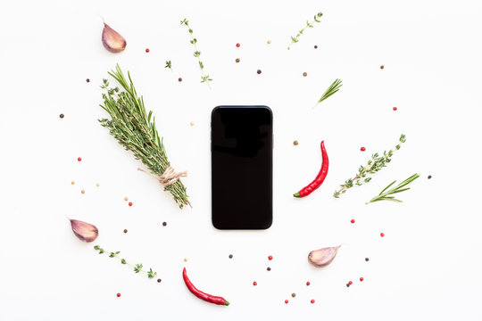 Smartphone with greens herbs and spices around