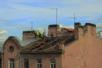Fototapeta na wymiar People repairing the roof of an old building 