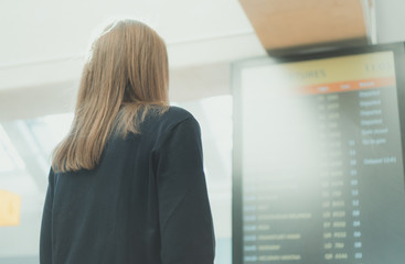 Woman in front of flight information board, checking her flight.