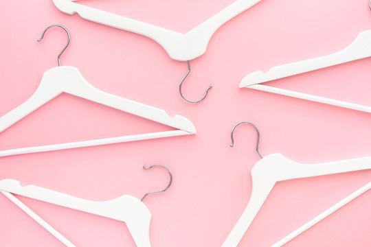 White hangers on pastel pink background