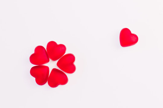 Concept of flower made of heart shaped red jelly sweets on isolated white background for Valentine's Day celebration. Top view. Copy space.