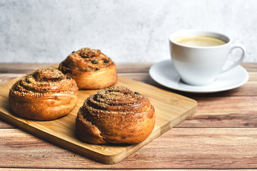 Perfect breakfast of two homemade cinnamon buns and coffee on wooden table. Rustic style. Close-up.