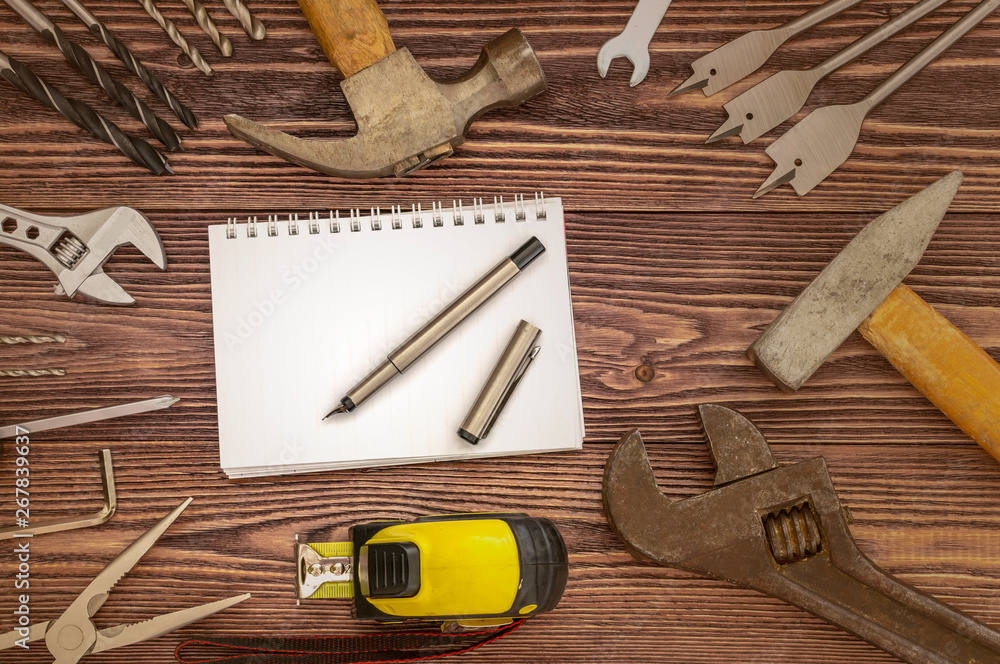 Wall mural tools and tape measure on wooden table with notepad and pen in the middle and vignetting