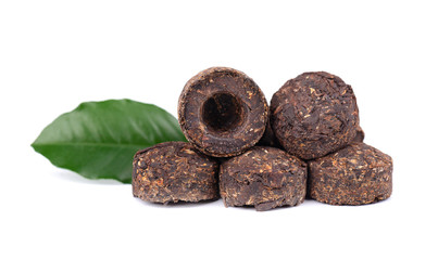 Aromatic black pu-erh tea, isolated on white background. Close up. Fermented and compressed Leaves into bricks. Round flat disc of puer tea. Healthy drink.