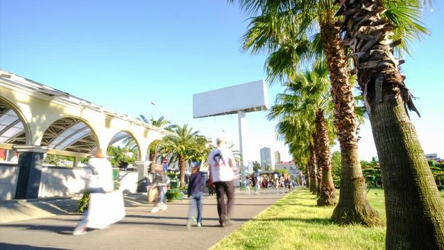 Time lapse shooting video. Large Billboard 6x3 in the city center at a high level. City traffic. Palm trees grow along the road. Walking street. Target audience.
