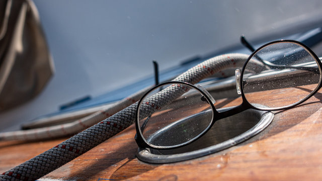 Dustyr and salty glasses laying on top of varnished surface with rope in the background. Authentic scene from the life of sailing