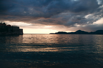 Obraz premium Beautiful view of the sunset or sunrise and the natural landscape with the sea and hills or mountains in Montenegro in the summer.