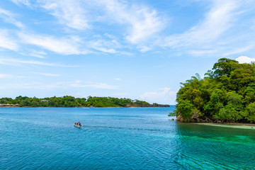 Tour boat with people sailing the beautiful turquoise ocean waters by Monkey Island (aka Pellew/Pelew/Pelu/ Princess Island) in San San, Port Antonio, off the coast of Portland Parish in Jamaica.