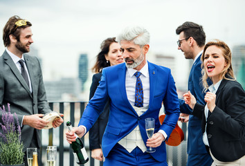 Fototapeta premium A group of joyful businesspeople having a party outdoors on roof terrace in city.