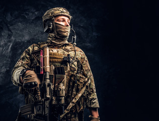 Modern special forces soldier in camouflage uniform looking sideways. Studio photo against a dark...