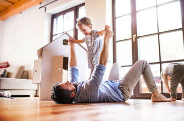 Two toddler children with father playing indoors at home.