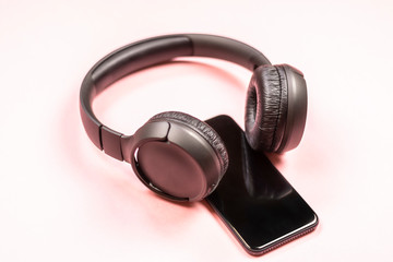 Close-up of smart phone with headphones on a pink background. (Top view). Listen to music.
