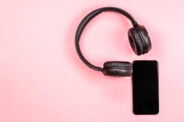 Close-up of smart phone with headphones on a pink background. (Top view). Listen to music.