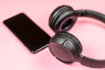 Close-up of smart phone with headphones on a pink background. (Top view). Listen to music.