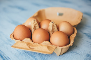 Eggs background. Closeup view of chicken eggs in carton box on wooden background. 
