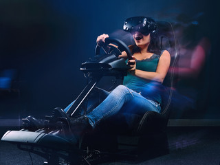 Woman wearing VR headset having fun while driving on car racing simulator cockpit with seat and wheel.