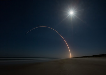 Delta 4 rocket launch into full moon lit sky as seen from Canaveral National Seashore in Floirda