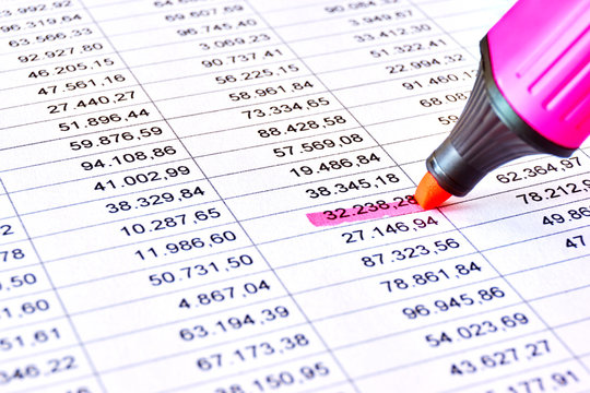 Red pink marker on a sheet of paper with printed financial numerical data table and marked numbers. Concept for accounting, budget, profit, tax and financial review. Image with selective focus    