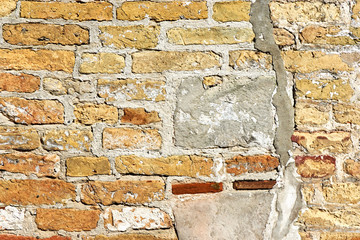 Background of an old weathered wall and repairs with yellow, orange and brown-red bricks      