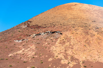 Timanfaya National Park, mountains of fire at Lanzarote, Canary Islands, Spain. Unique panoramic view of spectacular corrosioned lava layers flows of a huge volcano cone.