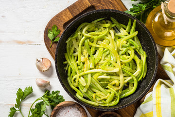 Zucchini noodles in frying pan on white.