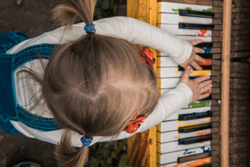 Little girl plays the color piano. Children's hands. Piano keys.