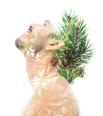 Double exposure of a young bare-chested man’s portrait blended with bright green leaves, showing...