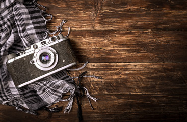 Old retro camera on vintage brown wooden board with black and white checkered scarf. abstract background. Top view.Copy space for text.