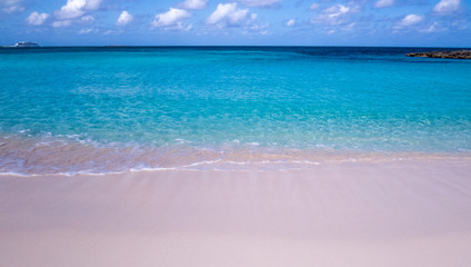Beautiful day at the beach with passing clouds and a cruise ship over the Atlantic Ocean. Nassau, The Bahamas.