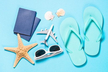 Blue flip flops, sunglasses and starfish on blue background.