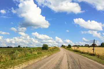 Fototapeta na wymiar Empty asphalt road, rural fields and blue sky with white clouds. Perspective, background