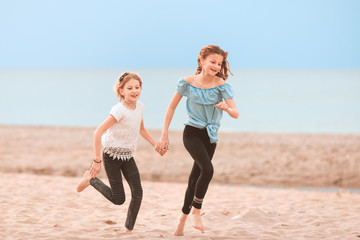 Two young girls running, playing on the beach