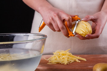 young woman in an apron cuts potatoes