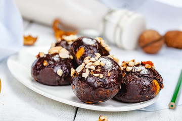 Cookie balls with chocolate glaze and walnuts on white plate. Close up