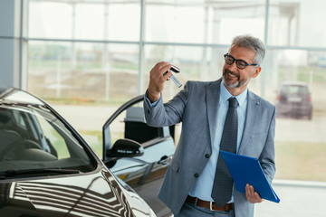 car dealer agent holding car keys in car showroom