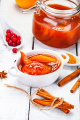Persimmon jam in glass jar on wooden  background. Close up
