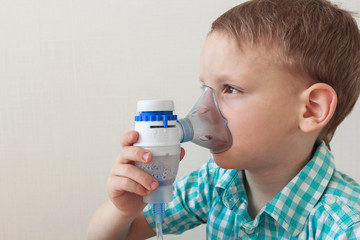 Child using inhaler nebulizer at home. Treatment of asthma or bronchitis. Respiratory disease...