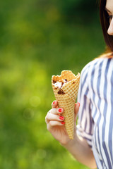 Ice cream close-up. Young beautiful girl with long flowing hair holding ice cream. Bright sunny day. Natural background. Soft focus. Summer concept. Copy space