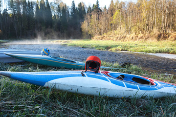 Canoe with helmet on the shore of mountain river. Sunrise. Morning mist. Extreme sport, kayaking