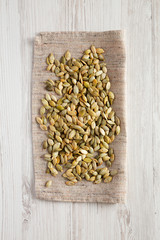 Roasted pumpkin seeds on a white wooden background, top view. Flat lay, overhead, from above.