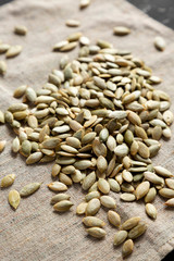 Roasted pumpkin seeds on cloth over black surface, side view. Close-up.