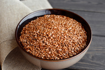 flax seeds in bowl with linen fabric on wooden background
